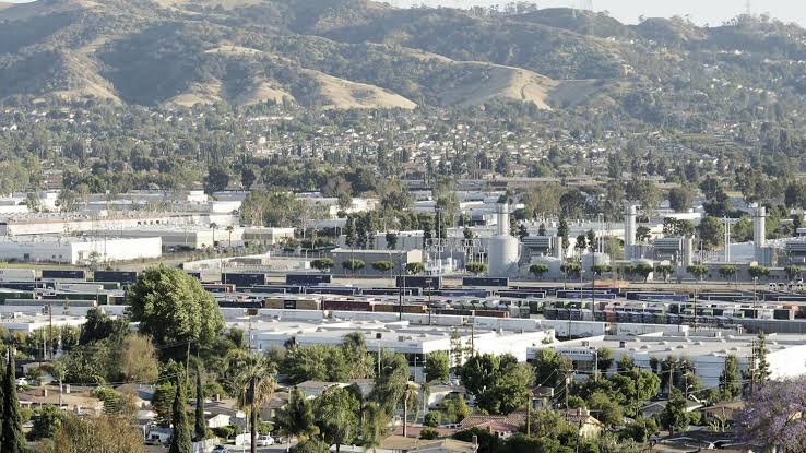 Industrial rail yard beneath sunlit hills and suburban neighborhoods